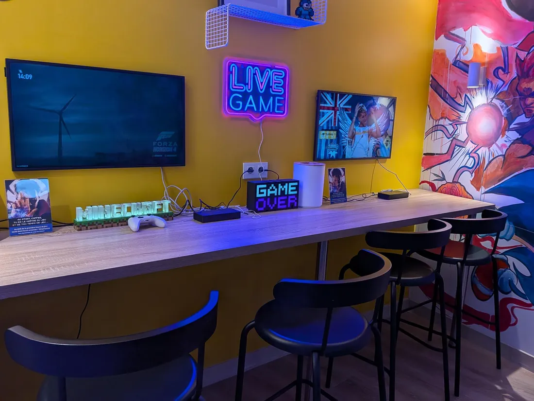 Comptoir jaune avec enseigne néon Live Game et tabourets hauts